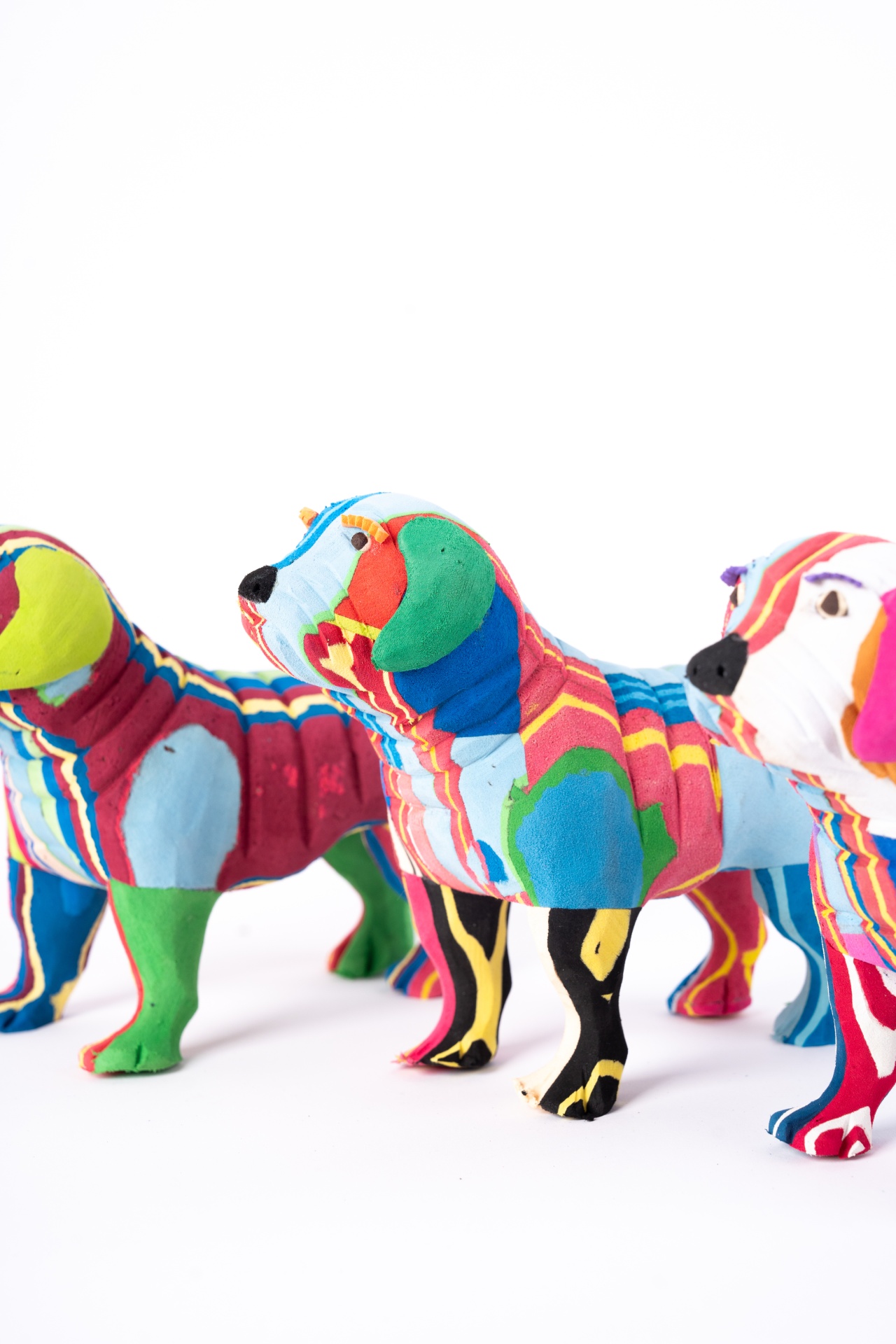 Cão Buldog M Três bonecos de cães em tecido colorido com padrões abstratos