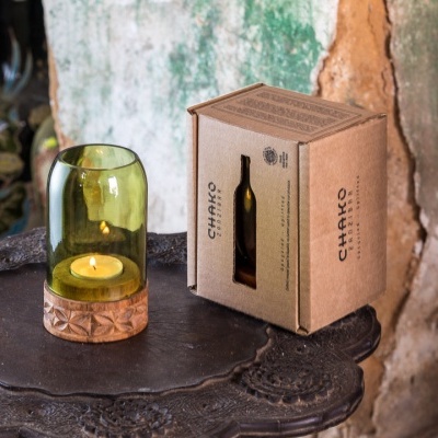 Vela pequena em vidro verde com suporte de madeira e embalagem de cartão