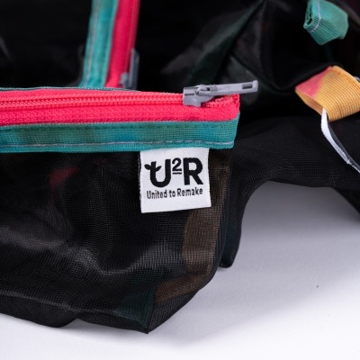 Bolsa preta com fecho vermelho e verde e etiqueta U2R United to Remake