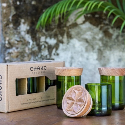 Três frascos verdes de vidro com tampas de madeira e caixa de embalagem