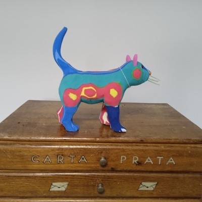 Figura decorativa de gato colorido sobre móvel de madeira com gavetas