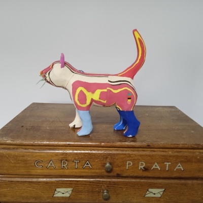 Figura de gato em tecido colorido sobre móvel de madeira com inscrição