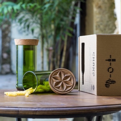 Frascos verdes com tampas de madeira e caixa de cartão numa mesa redonda