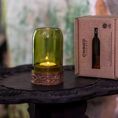 Castiçal verde com vela acesa ao lado de caixa de papelão CHIARO