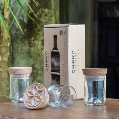 Frascos de vidro com tampas de madeira e embalagem CHAKRA numa mesa redonda de madeira