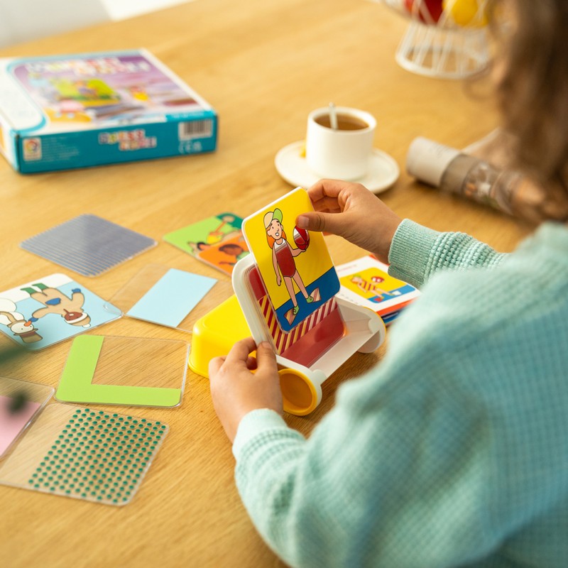 Mãos segurando carta ilustrada de mulher com pesos, cartas espalhadas em mesa de madeira clara