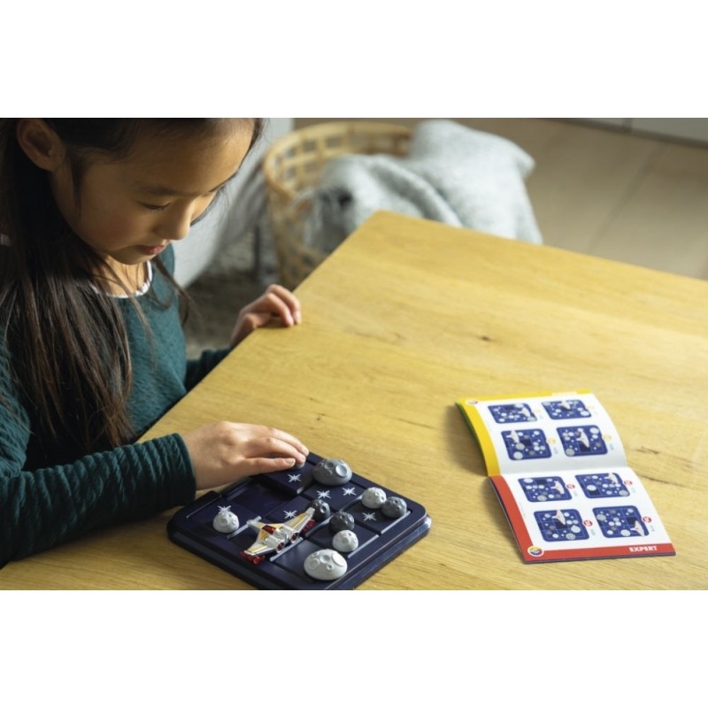 Criança a jogar jogo de tabuleiro espacial com peças e manual aberto numa mesa.