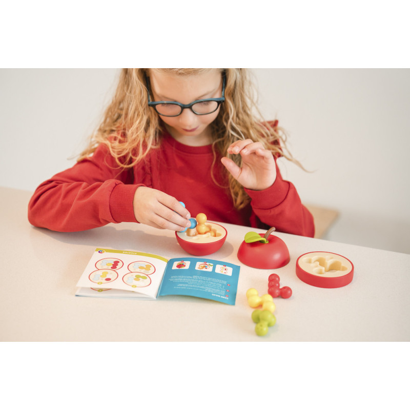 Criança a montar puzzle de maçã colorida com livro de instruções