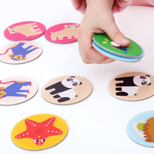 Fichas redondas de jogo da memória com desenhos de animais coloridos, mão segurando várias fichas, fundo branco