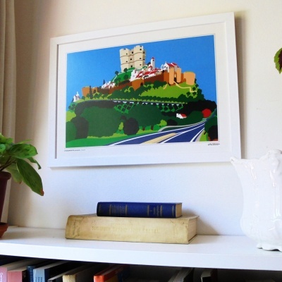 Ilustração colorida de castelo em quadro branco sobre estante com livros, planta e jarro