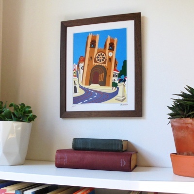 Quadro colorido de igreja em moldura de madeira acima de prateleira com plantas e livros