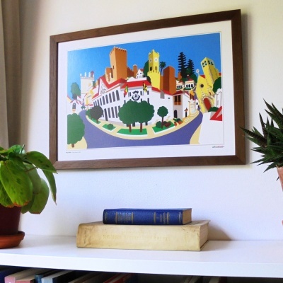 Quadro colorido de vila com casas, plantas e livros numa estante branca.