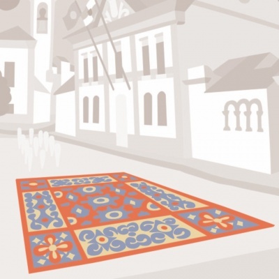 Tapete retangular colorido com padrões florais e geométricos numa rua com edifícios tradicionais