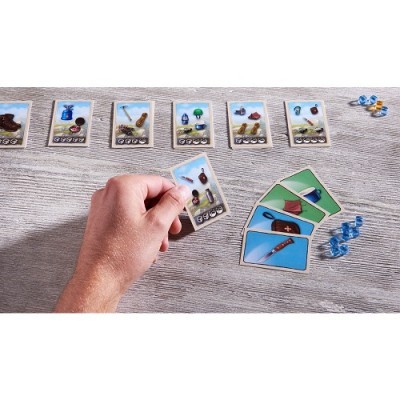 Jogo de cartas com cartas de objetos e fichas azuis numa mesa cinzenta