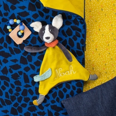 Brinquedo de peluche cão amarelo com nome Noah sobre tecido azul e amarelo