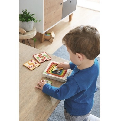 Criança com brinquedo de encaixe num ambiente interior com móvel e planta