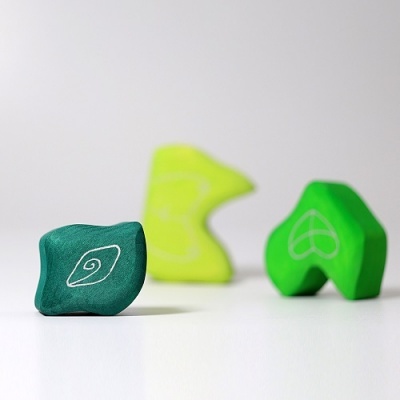 Três peças de madeira coloridas com desenhos em branco sobre superfície branca