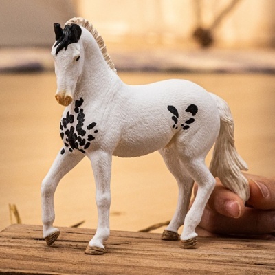 Figura de cavalo branco com manchas pretas em superfície de madeira