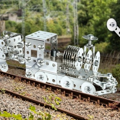 Maqueta metálica prateada de um comboio sobre carris com parede de controlo Kpl