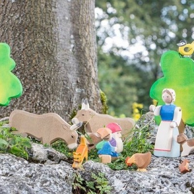 Figuras de madeira coloridas de uma cena rural com pessoas, animais e árvores em ambiente exterior