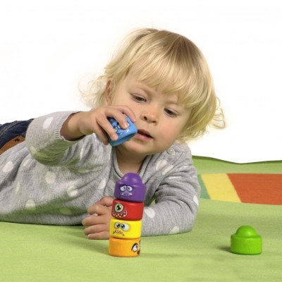 Criança a empilhar blocos coloridos com olhos num tapete verde