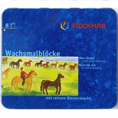 Caixa azul metálica da Stockmar com blocos de cera e ilustração de crianças e cavalos no campo