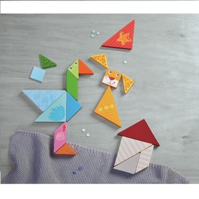 Peças de madeira coloridas formando um pato, um cão e uma casa sobre fundo cinza com tecido lilás