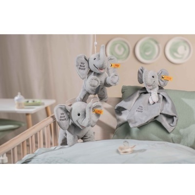 Peluches de elefante cinzentos pendurados e apoiados em cama de bebé azul clara com decoração suave