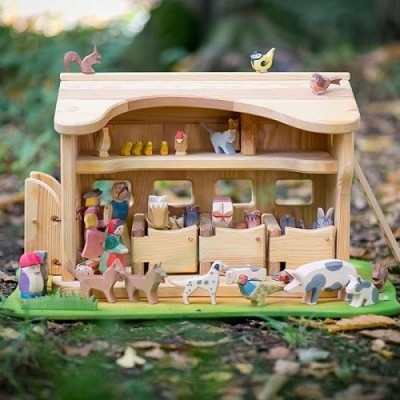 Casa de fazenda em madeira com figuras de animais e pessoas pintadas à mão sobre relva