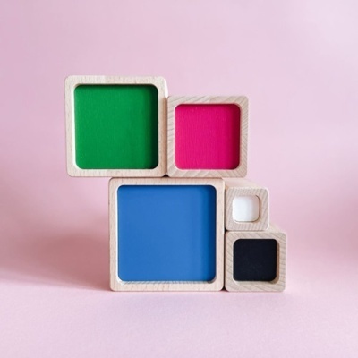 Blocos de madeira quadrados coloridos empilhados sobre superfície rosa