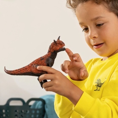 Menino a brincar com dinossauro de brinquedo vermelho e preto