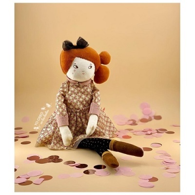 Boneca de pano com vestido xadrez e cabelo castanho avermelhado sentada entre confetes rosa e castanhos