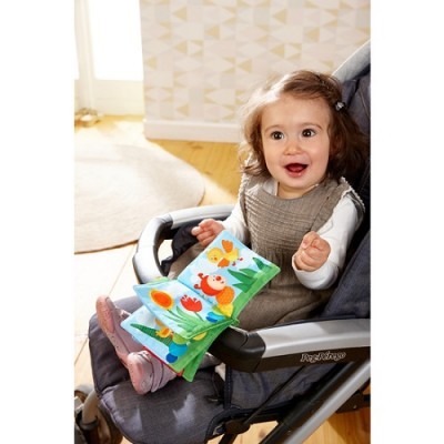 Criança segurando livro de pano colorido numa cadeira de bebé