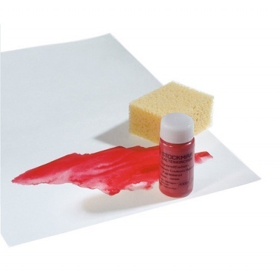 Frasco pequeno de corante vermelho com tampa branca, esponja amarela e mancha vermelha em papel branco