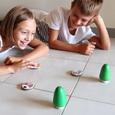 Crianças a jogar com peças de madeira verdes e naturais com faces de animais.