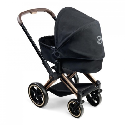 Carrinho de bebé preto com estrutura metálica bronze e rodas.