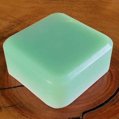 Caixa quadrada verde translúcida com cantos arredondados em superfície de madeira