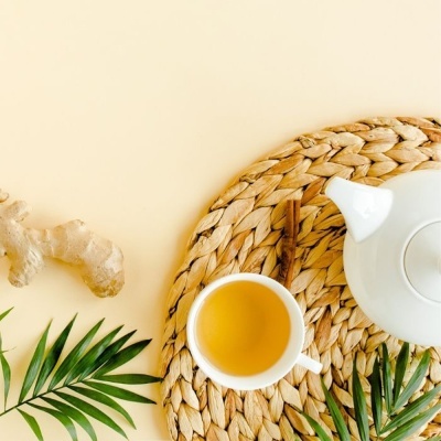 Chávena e bule branco com chá e elementos naturais num fundo bege