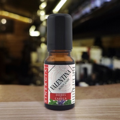 Frasco pequeno de vidro âmbar com tampa preta e etiqueta branca com texto e motivos florais