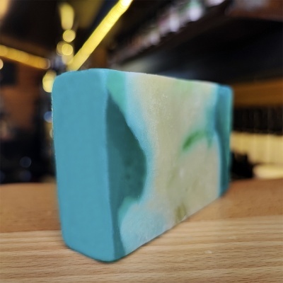 Barra de sabonete azul, branco e verde sobre superfície de madeira