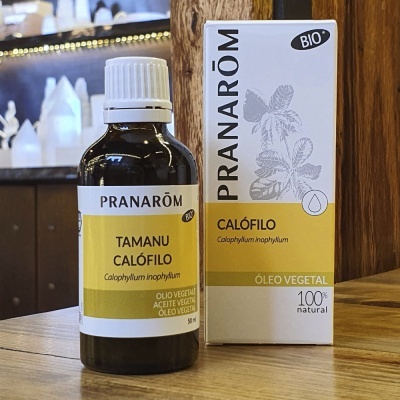 Frasco e embalagem de óleo vegetal Pranarôm Tamanu Calófilo 50ml sobre mesa de madeira