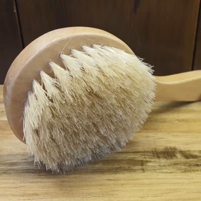 Escova de madeira com cerdas naturais claras em mesa de madeira