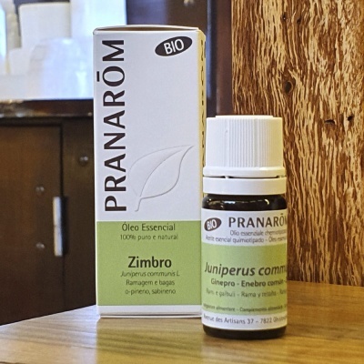 Frasco e embalagem de óleo essencial PRANARÔM BIO Zimbro em superfície de madeira