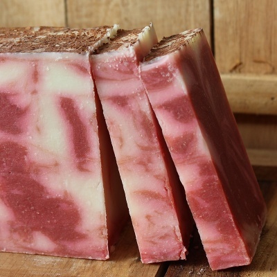 Barras de sabão artesanal rosa e branca sobre tábua de madeira