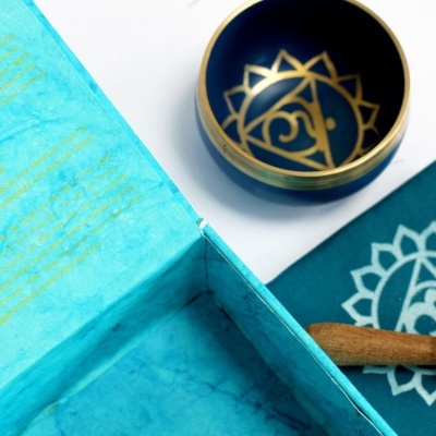 Conjunto de tigela sonora azul escuro com padrão dourado, almofada azul e bastão de madeira em caixa azul clara