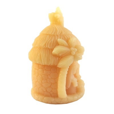 Vela amarela em forma de casa com textura de pedras e flor decorativa