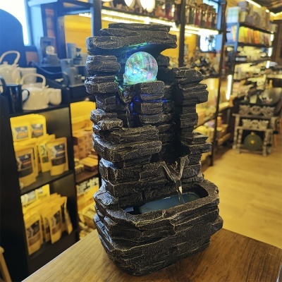 Fonte decorativa de pedra negra com esfera luminosa em loja