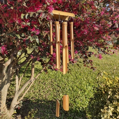 Sino dos ventos de madeira pendurado numa árvore florida