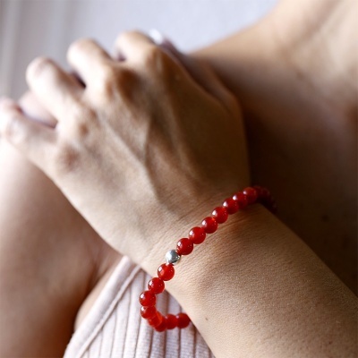 Pulseira de contas vermelhas com uma conta prateada no pulso