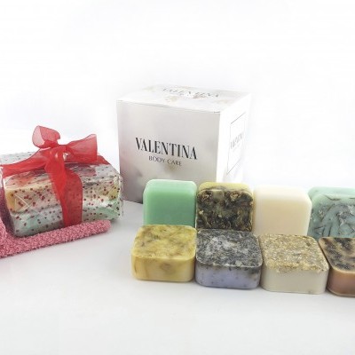 Conjunto de sabonetes artesanais coloridos e uma caixa branca Valentina Body Care com toalha rosa